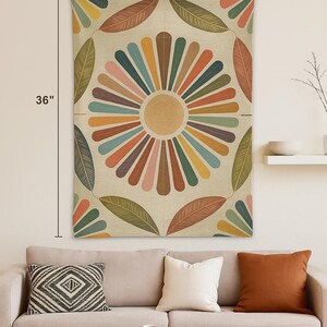 May include: A decorative wall tapestry featuring a large, colorful floral design. The tapestry is 26 inches wide and 36 inches long. The design includes a central sunburst pattern with radiating stripes in various colors, surrounded by leaf-shaped elements.