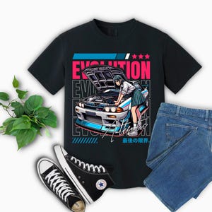 May include: Black t-shirt with a graphic of a blue and white car with a woman standing next to it. The text "EVOLUTION" is in pink and blue letters. The text "Authentic" is in white letters. The text "最後の限界" is in black letters.