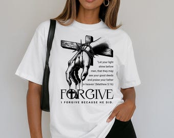 May include: White t-shirt with a black and white graphic of a hand pierced by a cross and a crown of thorns. The word "FORGIVE" is printed below the graphic, along with a Bible verse.