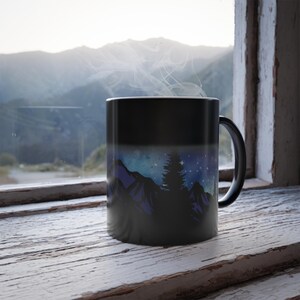 May include: Black heat-sensitive mug with a design of a mountain range and starry sky that appears when hot liquid is added. The mug has a black handle.