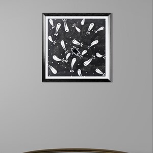 May include: A framed artwork featuring a black background with white, ghost-like figures and a star. The figures are scattered across the canvas, creating a whimsical and slightly spooky design. The frame is black.