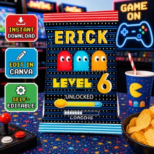 Op de afbeelding: Een feestzakje met een retro videogame thema. De zak heeft de naam "ERICK", het nummer "6" en gepixelde geesten. De zak heeft ook de woorden "UNLOCKED" en "LOADING". Een beker met een Pac-Man ontwerp en een kom chips zijn ook zichtbaar.