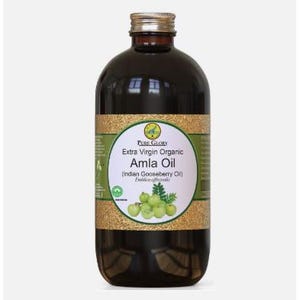 Puede incluir: Una botella de vidrio marrón oscuro de aceite de Amla orgánico extra virgen Pure Glory (aceite de grosella india). La botella tiene una etiqueta dorada con un diseño de hojas verdes y el texto "Pure Glory Extra Virgin Organic Amla Oil (Indian Gooseberry Oil)".