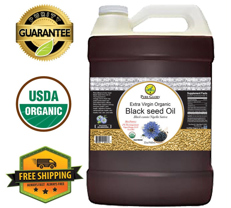 Puede incluir: Una jarra de un gal&oacute;n de aceite de semilla negra org&aacute;nico extra virgen Pure Glory. La etiqueta es marr&oacute;n con detalles dorados y presenta una semilla de comino negro. La etiqueta tambi&eacute;n indica "Comino negro/Nigella Sativa" y "32oz/960ml".