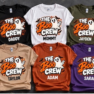 May include: Six short-sleeve t-shirts in black, white, olive, tan, orange, and purple. Each features a graphic of a ghost making a peace sign with the text THE BOO CREW and a personalized name: DADDY, MOMMY, JAYDEN, TAYLOR, ADAM, or SARAH.