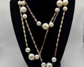 Collar Hattie Carnegie de 137 cm (54 pulgadas) de largo, estilo ópera. Perlas sintéticas barrocas de mediados de siglo en una cadena única de tono dorado. Circa 1950.