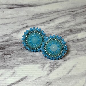 Beaded earrings, handmade with blue seed beads, pale blue resin centre, blue rhinestones and stainless steel lever back post, faux suede