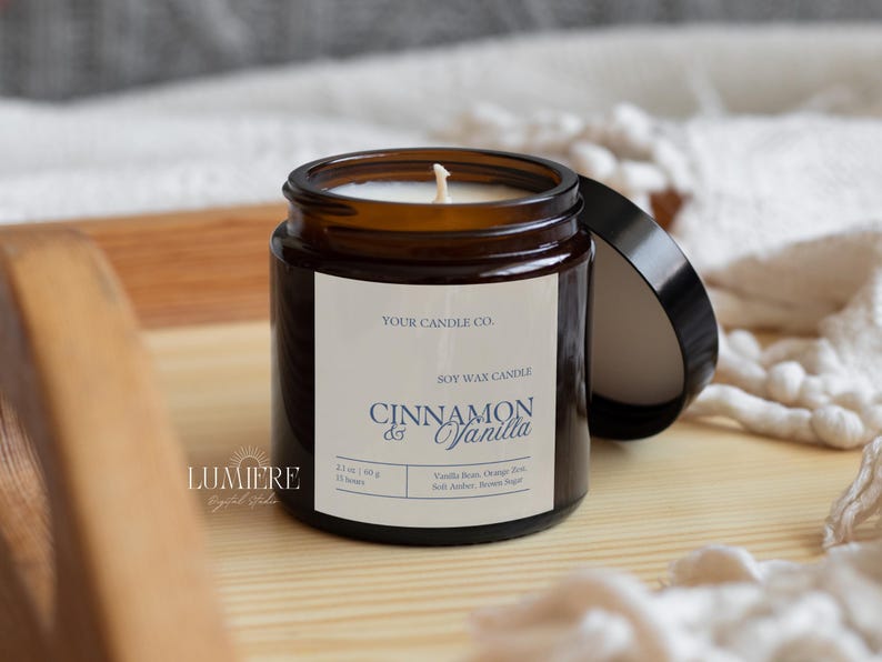 K&ouml;nnte beinhalten: Eine Sojawachs-Kerze in einem braunen Glas mit schwarzem Deckel. Auf dem Etikett steht "Cinnamon & Vanilla" und die Inhaltsstoffe sind aufgelistet. Die Kerze steht auf einem Holztablett, im Hintergrund ein wei&szlig;er Stoff. Das Glas enth&auml;lt 60 g Wachs.