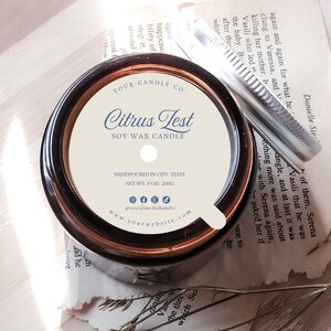 May include: A brown glass candle jar with a white label that reads "Citrus Test Soy Wax Candle". The label also includes the company name, website, and social media handles. The candle is hand-poured and weighs 8 ounces or 200 grams.