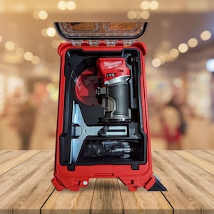 May include: A red and black power tool kit with a clear lid. The kit contains a red and black router, a silver metal guide, and other accessories. The kit is open, revealing the tools inside. The background is blurred.