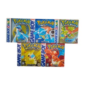 May include: Five vintage Pokémon Game Boy Color game boxes. The boxes feature the Pokémon characters Blastoise, Charizard, Pikachu, Lugia, and Ho-Oh. The boxes are labeled Silver Version, Blue Version, Gold Version, Special Pikachu Edition, and Red Version.