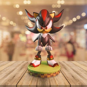 May include: A detailed figurine of Shadow the Hedgehog, a character from the Sonic the Hedgehog franchise. The figure is primarily black with red and yellow accents, standing on a green and brown base. The figurine is posed in a standing position.