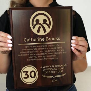 May include: A wooden plaque with a dark brown finish, featuring the name "Catherine Brooks" and a dedication message. The plaque includes a logo, the number "30" in a circular design, and the year "2026".