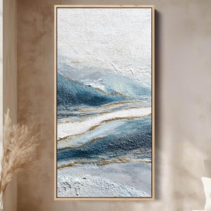 Könnte beinhalten: Abstrakte, strukturierte Wandkunst in einem rechteckigen Holzrahmen. Das Kunstwerk zeigt ein mehrschichtiges Design mit Weiß-, Blau- und Goldtönen. Die strukturierte Oberfläche erzeugt ein Gefühl von Tiefe und Dimension, geeignet für die Inneneinrichtung.