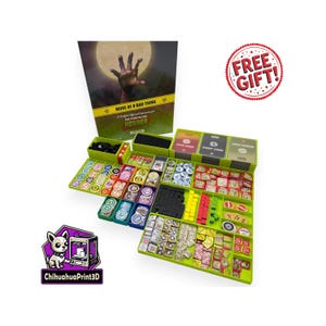 Puede incluir: Un juego de mesa con una bandeja de almacenamiento verde llena de piezas, cartas y fichas. La ilustración de la caja presenta una mano de zombi que se extiende hacia una luna llena. El texto en la caja dice "MORE OF A BAD THING HORROR". También es visible una pegatina de "FREE GIFT!".