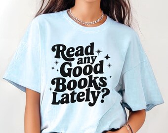 May include: Light blue t-shirt with the text "Read any Good Books Lately?" in a black, retro font. The shirt has a relaxed fit and short sleeves. The design includes star accents around the text, perfect for book lovers.