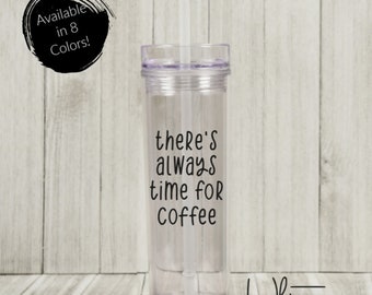 May include: Clear plastic tumbler with a straw and a black vinyl decal that reads "there's always time for coffee". The tumbler is on a wood background.