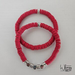 May include: Two red beaded bracelets with silver spacers. The smaller bracelet has a silver clasp.