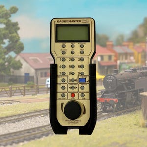 May include: A black and gold remote control with a digital display and buttons for controlling a model train. The remote control is labelled "Gaugemaster Prodigy Advance Controller".