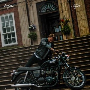 May include: A man wearing a black leather jacket sits on a black motorcycle in front of a brick building. The motorcycle has a chrome exhaust pipe and a black seat.