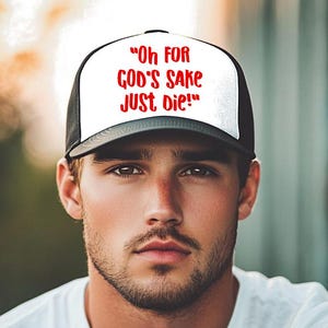 May include: A black and white trucker hat with the text "Oh FOR GOD'S SAKE JUST DIE!" in red. The hat is worn by a person wearing a white t-shirt.