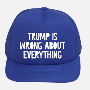 May include: A royal blue trucker hat with a white mesh back and a curved brim. The front of the hat features the white text "TRUMP IS WRONG ABOUT EVERYTHING".