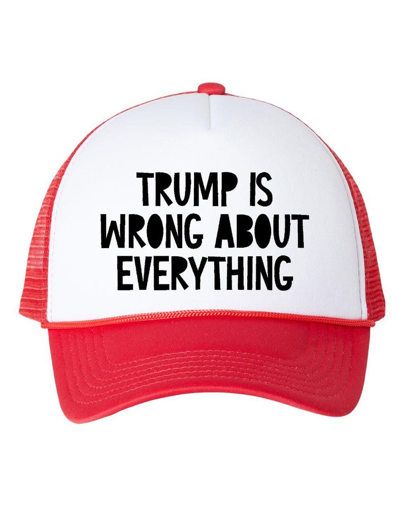 May include: A red and white trucker hat with the text "TRUMP IS WRONG ABOUT EVERYTHING" in bold black letters. The hat has a white front panel, a red brim, and a red mesh back.