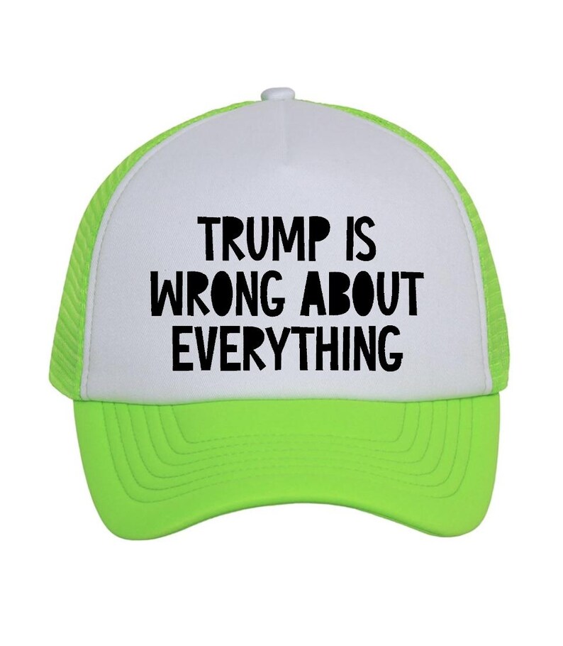 May include: A neon green and white trucker hat with the text "TRUMP IS WRONG ABOUT EVERYTHING" in bold black letters. The hat has a white front panel and a neon green mesh back and brim.