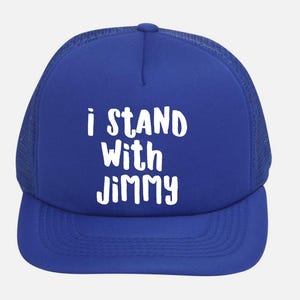 May include: A royal blue trucker hat with a white mesh back and a curved brim. The front of the hat features the white text "i STAND With JIMMY". This hat is a stylish accessory.