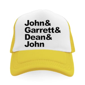 May include: A yellow and white trucker hat featuring a white front panel with the black printed text John & Garrett & Dean & John. The cap has a yellow brim and yellow mesh side and back panels, with a structured crown and a curved visor design.