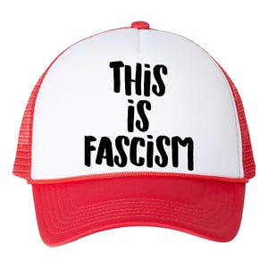 May include: A red and white trucker hat with the text "THIS IS FASCISM" in black block letters. The hat features a red brim and mesh back, with a white front panel.