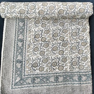 May include: A white cotton quilt with a floral pattern in shades of brown and grey. The quilt has a border with a paisley design.