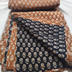 May include: A reversible quilt with a brown floral pattern on one side and a black floral pattern on the other side. The quilt is made of cotton and is quilted with a diamond pattern.