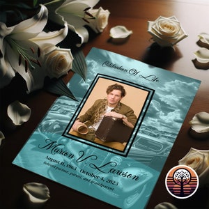 May include: A teal blue memorial booklet with a photo of a person in a brown shirt and a suitcase. The text on the booklet reads "Celebration of Life" and "Marion V. Lawson August 11, 1963 October 4, 2023 Beloved partner, parent, and grandparent".