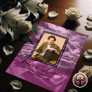 May include: A memorial card with a photo of a person, framed in black, against a purple sky background. The card reads "Celebration Of Life" and includes the name "Marion V. Lawson" with birth and death dates. White lilies and roses surround the card.