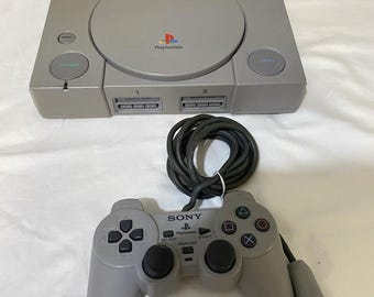 Consola original Sony PlayStation 1 PS1, paquete de mando DualShock y cable de alimentación AV