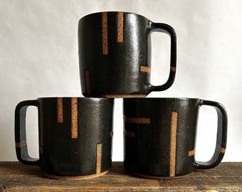 Black handmade ceramic mug with abstract geometric lines