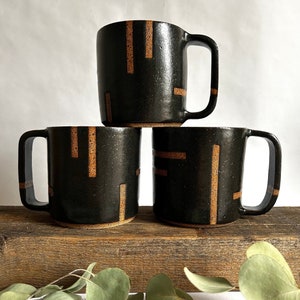 Black handmade ceramic mug with abstract geometric lines