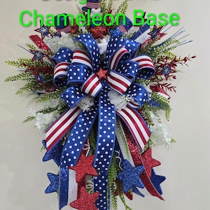 K&ouml;nnte beinhalten: Ein patriotischer Kranz mit rot-wei&szlig;-blauen B&auml;ndern in Punkt- und Streifenmustern, verziert mit glitzernden Sternen und gr&uuml;nem Blattwerk. Der Text 'Designed on a Chameleon Base' und 'Not included in listing' ist sichtbar.