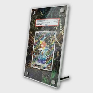 Op de afbeelding: Een ingelijste Pokémon-verzamelkaart met een kleurrijke illustratie van Blastoise. De kaart is beoordeeld en ingekapseld in een heldere acryl display met een standaard. De lijst heeft een donkere achtergrond met een ontwerp met een natuurthema en de tekst "2023 Pokemon Mew EN Blastoise ex Special Illustration Rare".