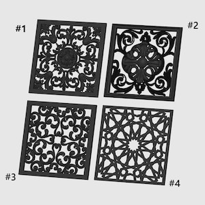 Könnte beinhalten: Vier schwarze dekorative Paneele mit aufwendigen, symmetrischen Designs. Jedes quadratische Paneel weist ein einzigartiges Muster auf, darunter florale, Ranken- und geometrische Motive. Die Paneele sind mit 1 bis 4 nummeriert.