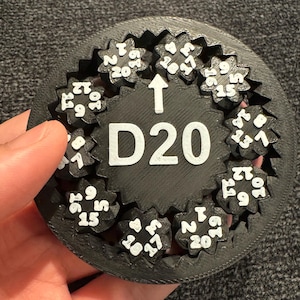 Op de afbeelding: Een zwarte D20 dobbelsteen spinner met witte nummers. De spinner heeft een tandwielachtig ontwerp met elk nummer op een apart tandwiel.