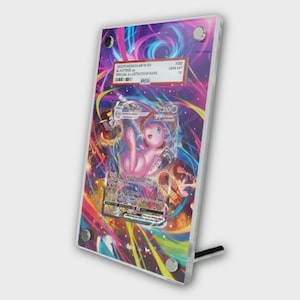 May include: A framed Pokémon card featuring Mew and Blastoise. The card is displayed in a clear acrylic stand with a colorful background. The card has text that reads "2023 POKEMON MEW EN BLASTOISE SPECIAL ILLUSTRATION RARE".