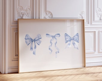 May include: A framed print of three blue watercolor bows on a white background. The print is hanging on a white wall in a room with white wainscoting and hardwood floors.