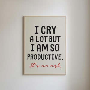 May include: A white framed print with black text that reads "I cry a lot but I am so productive. It's an art."