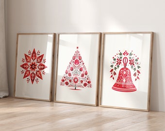 May include: Three framed prints with a white background and red and green illustrations. The first print features a red snowflake design. The second print features a red Christmas tree design. The third print features a red bell with green leaves.