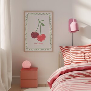 May include: A framed print with a white background and a green border. The print features a drawing of two red cherries with green stems and leaves. The text "ma ch&eacute;rie" is written below the cherries.
