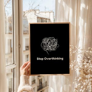 Pu&ograve; includere: Una stampa d'arte da parete stampabile in bianco e nero con un disegno a linea bianca di una bolla di pensiero aggrovigliata e il testo "Stop Overthinking".