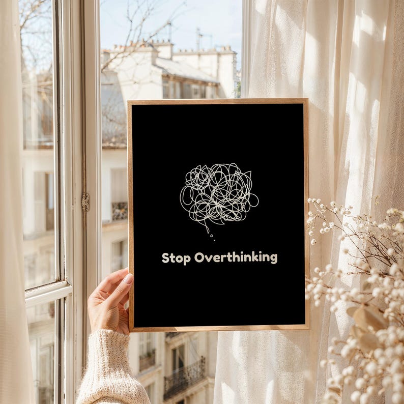 Pu&ograve; includere: Una stampa d'arte da parete stampabile in bianco e nero con un disegno a linea bianca di una bolla di pensiero aggrovigliata e il testo "Stop Overthinking".