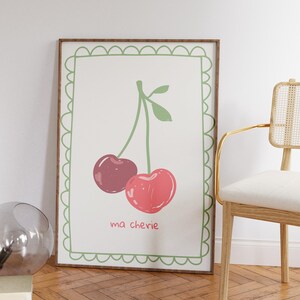 May include: A framed print with a green border and a white background. The print features a drawing of two red cherries on a green stem with the text "ma ch&eacute;rie" below.